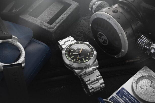 Delma Quattro dive watch on a steel bracelet surrounded by a regulator, dive weight and dive table