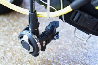Scuba regulator second stage with mouthpiece clipped to a BCD strap, yellow hose attached