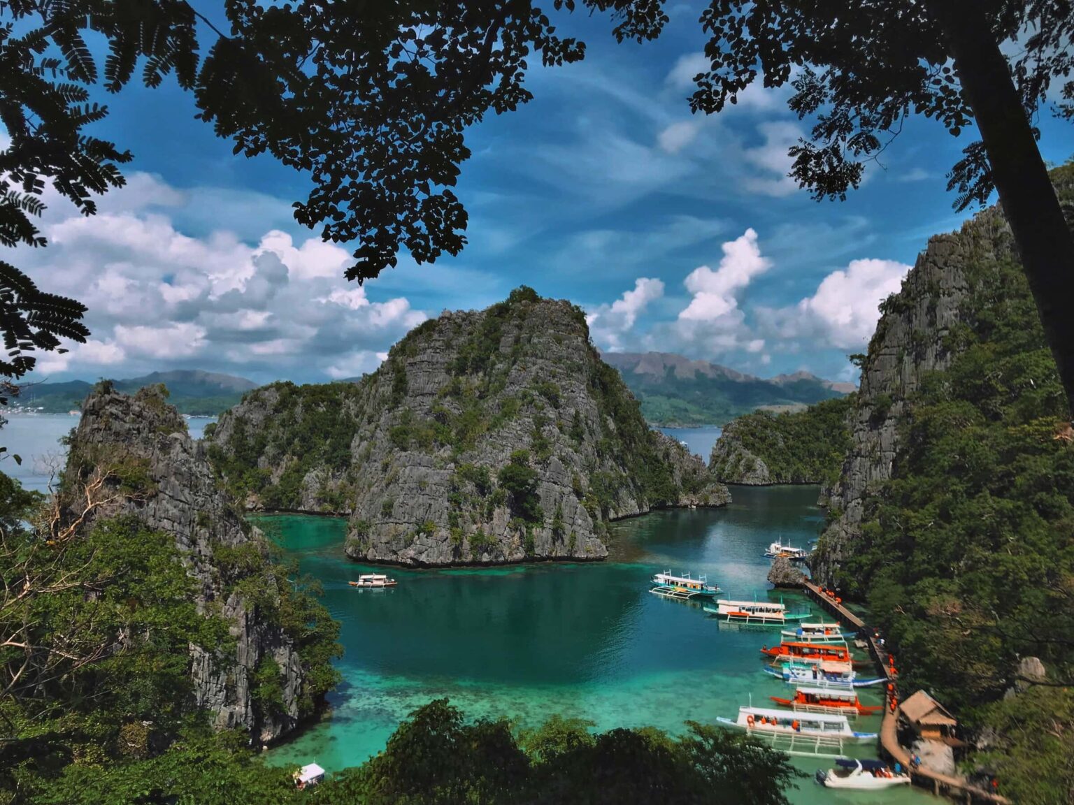 Limestone cliffs ring the turquoise lagoon and dive boats at Coron Bay, Palawan