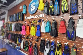 Wall of dive fins, masks and snorkels on display under the Scuba.com sign inside the store