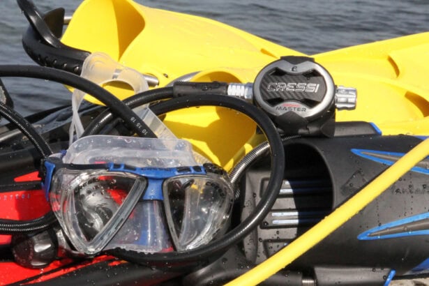 Cressi AC25 Master Cromo second stage resting on wet dive gear with a mask and yellow fins by the water