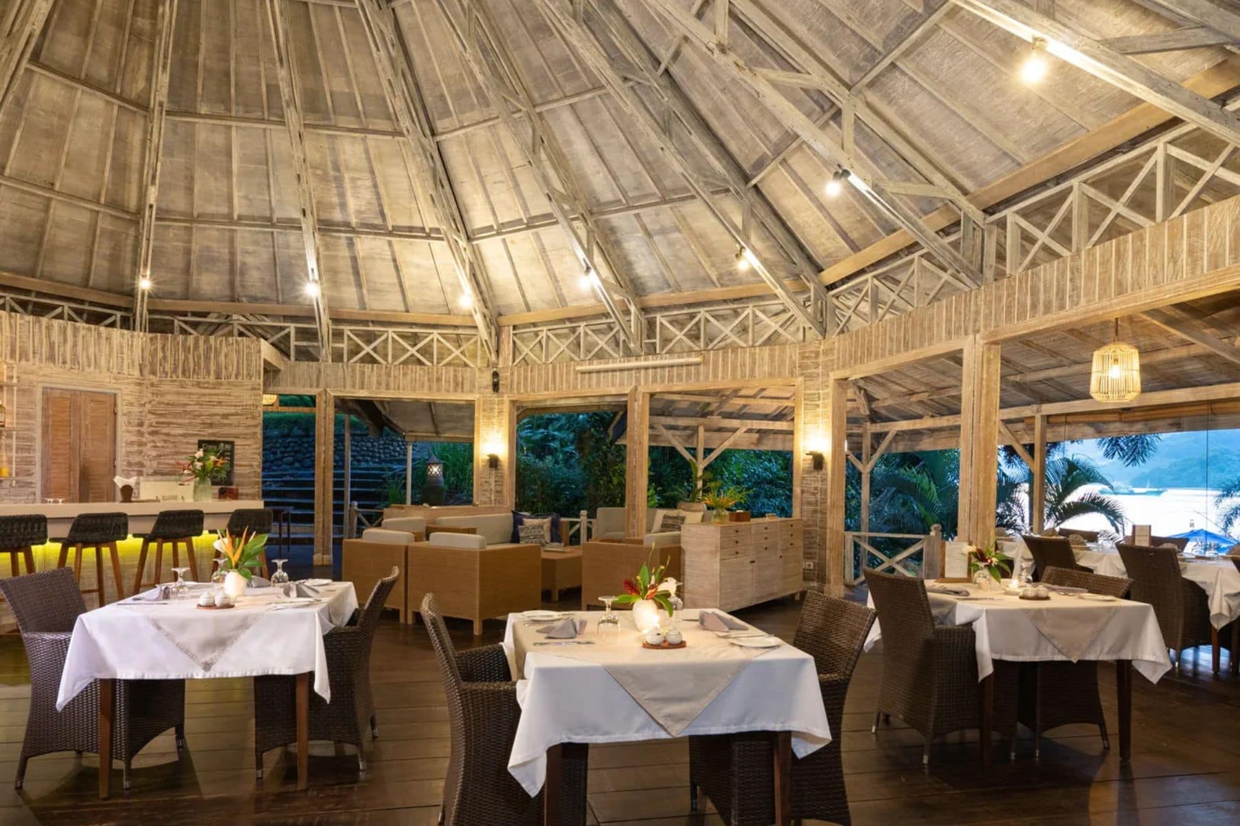 Open-air Lembeh Restaurant with thatched ceiling and tables set for dinner