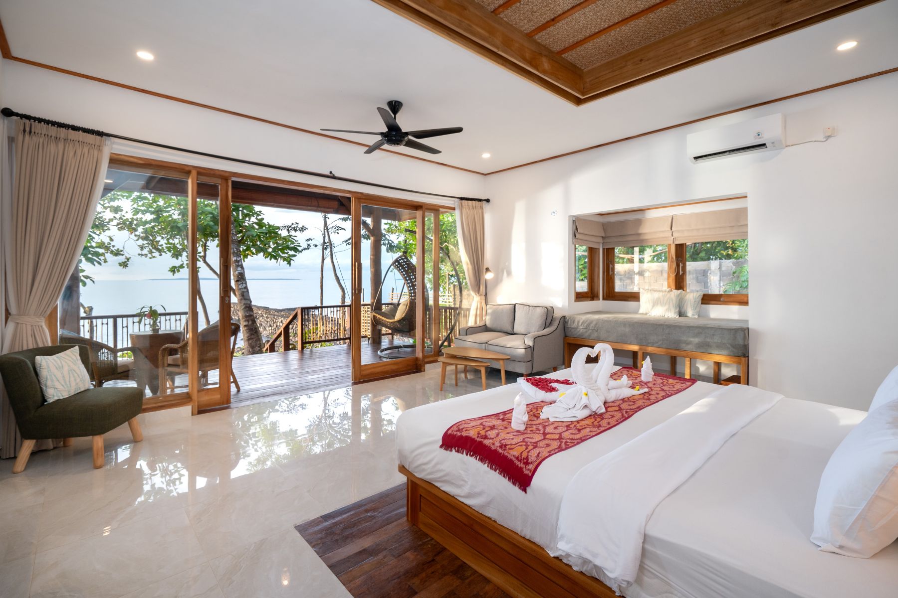Bedroom suite with four-poster netting bed opening onto an oceanfront balcony