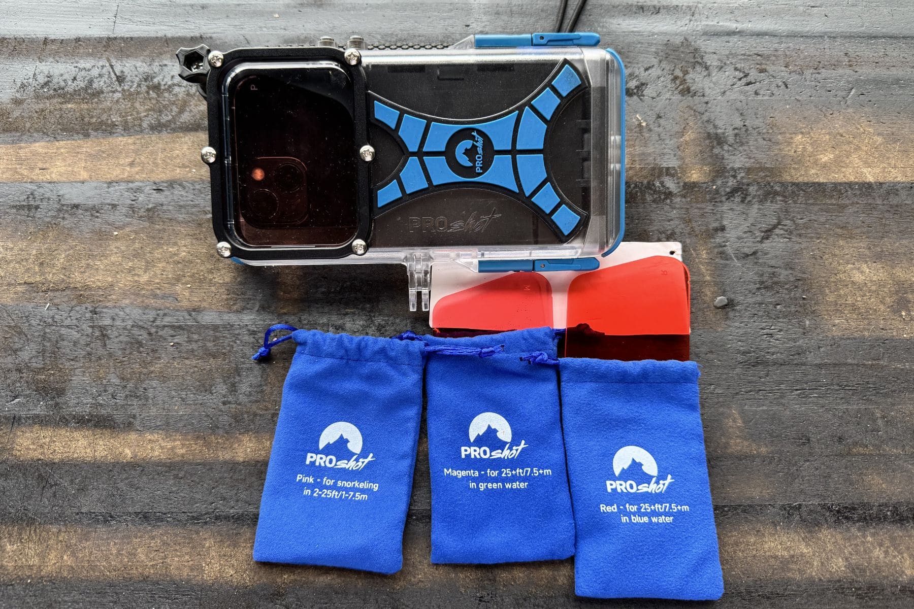 ProShot Dive Case with its red filter and three labelled ProShot colour filter pouches on wood