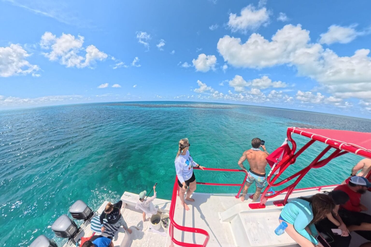 Divers on a boat looking out over turquoise water at the edge of Belize's Great Blue Hole
