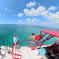 Divers on a boat looking out over turquoise water at the edge of Belize's Great Blue Hole