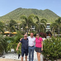 Mike Harterink, Peter Barnhoorn and Marieke van de Wetering standing together beside the pool at Golden Rock Resort, with The Quill volcano rising behind them on St. Eustatius