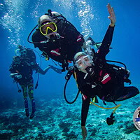 An amputee adaptive diver underwater alongside a Diveheart dive buddy