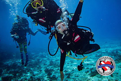 An amputee adaptive diver underwater alongside a Diveheart dive buddy