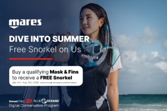 A snorkeller on a beach wearing a Mares mask and snorkel, beside the Dive Into Summer free snorkel promotion details