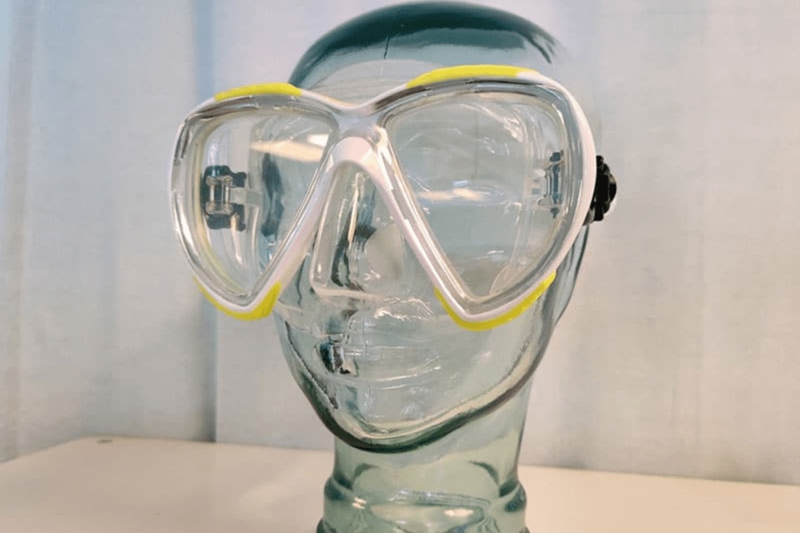 Oceanic Discovery twin-lens dive mask fitted on a glass mannequin head, showing the teardrop lens shape