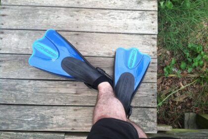 Cressi Palau fins in blue and black worn on a wooden deck, part of the Cressi Palau snorkel set