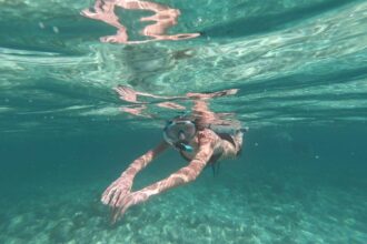 Snorkeler swimming just below the surface in clear turquoise water wearing a Seavenger Voyager mask and snorkel