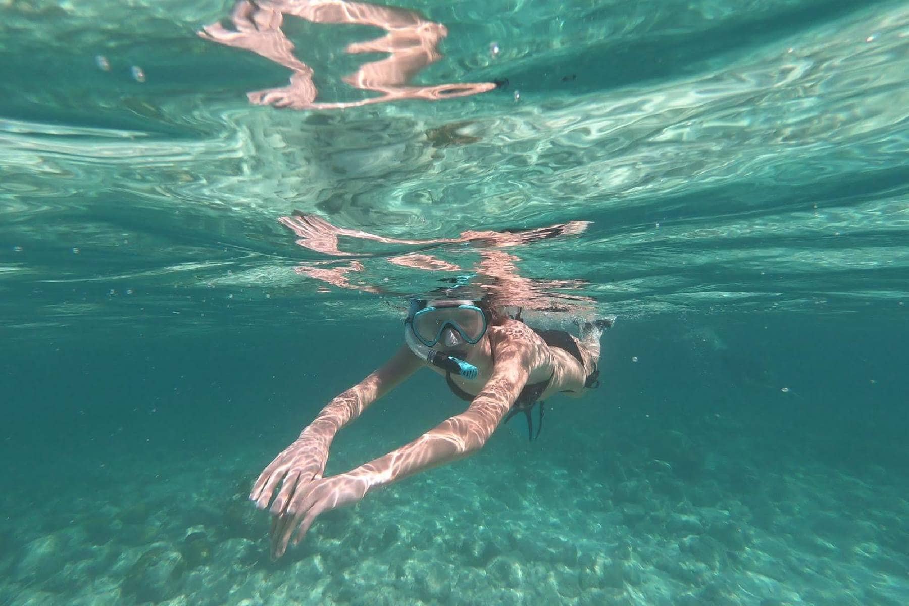 Snorkeler swimming just below the surface in clear turquoise water wearing a Seavenger Voyager mask and snorkel