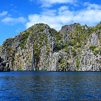 Limestone cliffs rise above blue water in Coron, Palawan