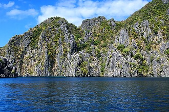 Limestone cliffs rise above blue water in Coron, Palawan
