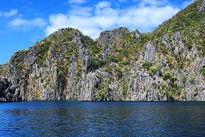 Limestone cliffs rise above blue water in Coron, Palawan