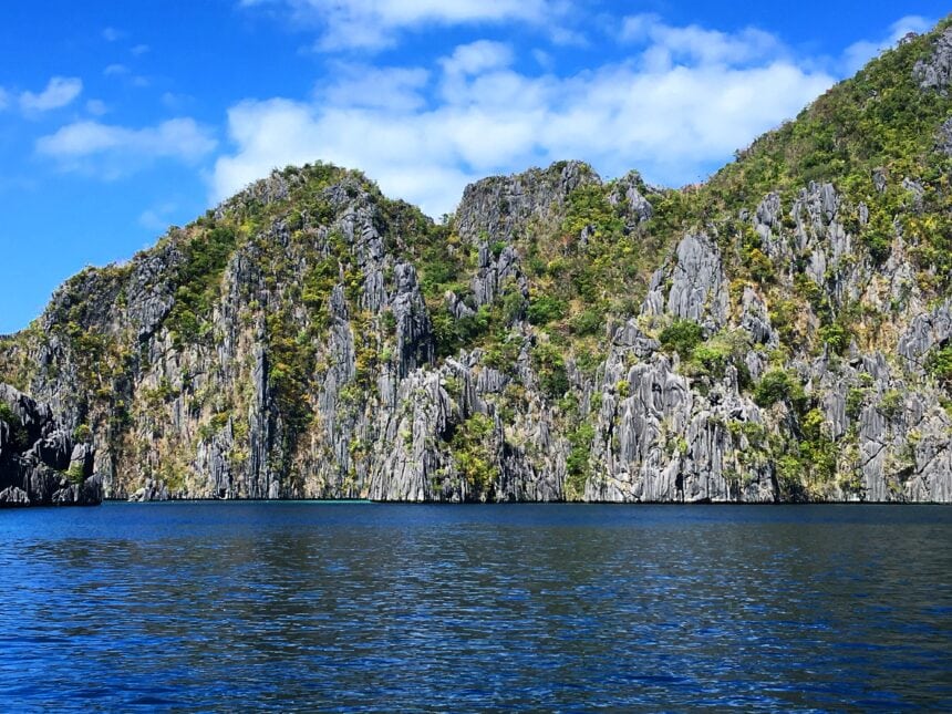 Limestone cliffs rise above blue water in Coron, Palawan